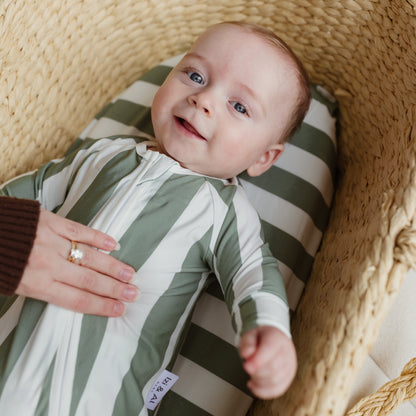 Baby lying on Sage Stripe bamboo baby cover in a pram bassinet by Izi & Al